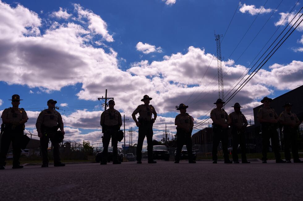 ARCHIVO - Agentes de la policía estatal de Illinois hacen guardia mientras un grupo de...