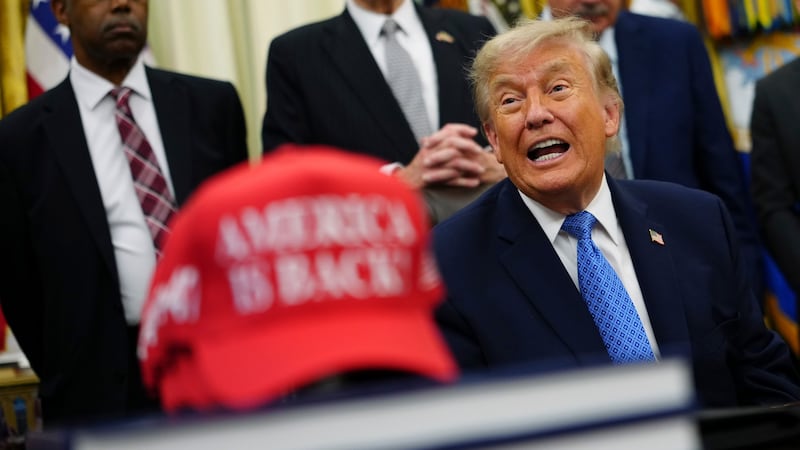 El presidente de Estados Unidos, Donald Trump, habla junto a una gorra roja que dice, en...